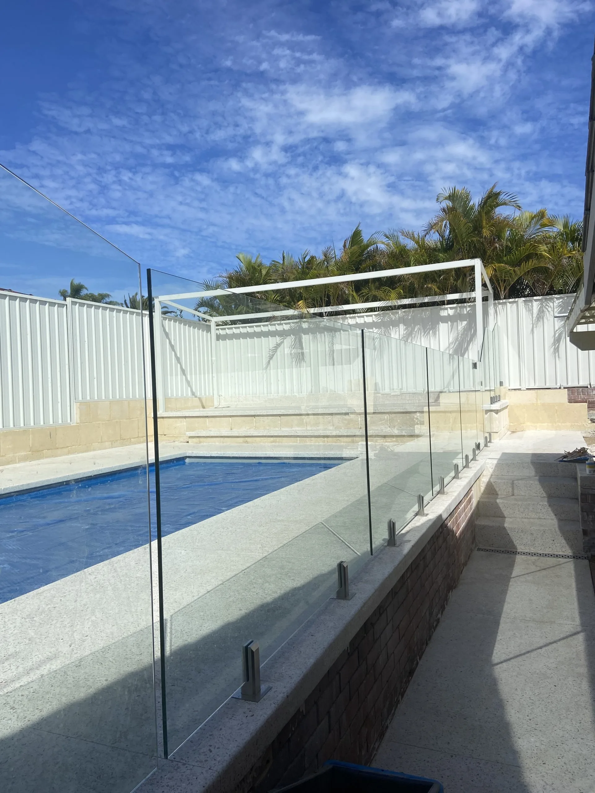 Frameless glass pool fence and steps beside a Townsville home
