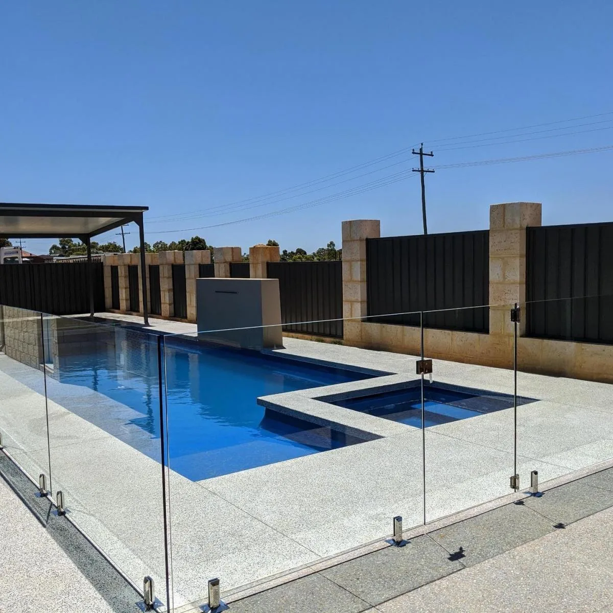 Frameless glass pool fencing beside a resort-style pool with a water feature