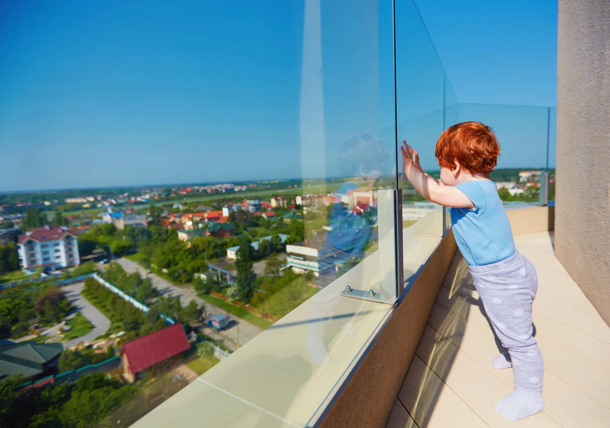 Child at a glass balustrade on a rooftop balcony