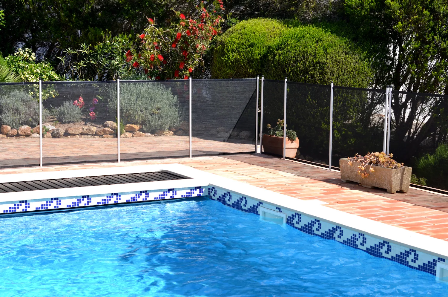 Removable mesh pool safety fence beside a home pool