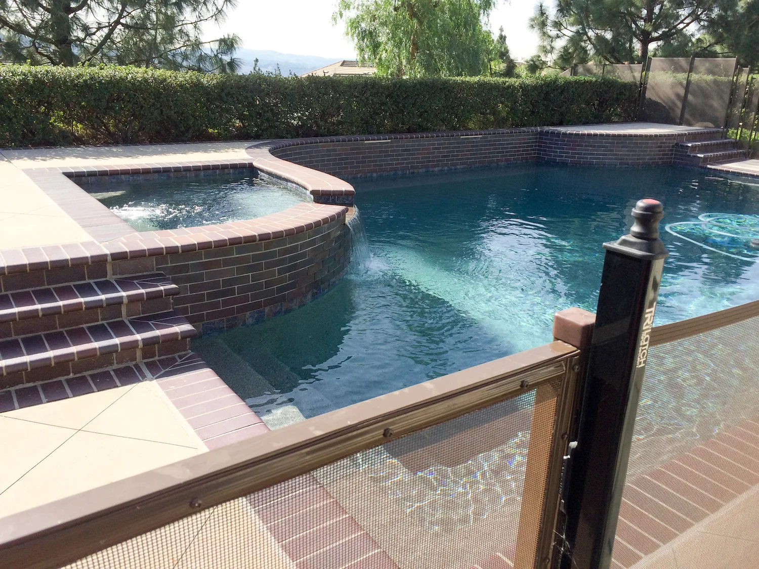 Pool fence gate and post beside a home pool