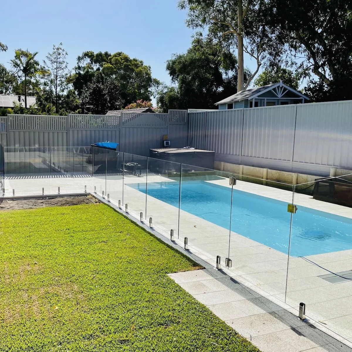 Frameless glass pool fence around a covered home pool